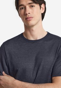 Mörkblå crew-neck t-shirt gjord av ett mjukt, strukturerat tyg. Korta ärmar och en avslappnad passform, med subtila variationer i färg.