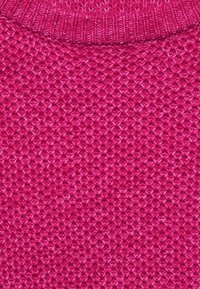 Tkany materiał w kolorze fuksji z fakturowanym, wypukłym wzorem. Kołnierz jest ściągaczowy, co dodaje głębi całej konstrukcji.