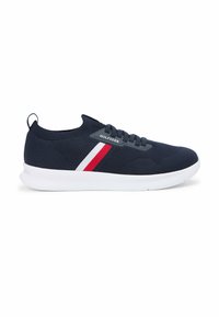 Granatowy dzianinowy sneaker z białymi i czerwonymi paskami po bokach, czarnymi sznurówkami, białą podeszwą oraz logo "Hilfiger" przy sznurówkach.