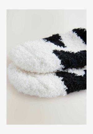 Calcetines borrosos en blanco y negro que presentan una textura suave, con un patrón de colores alternados y un diseño de punta redondeada.