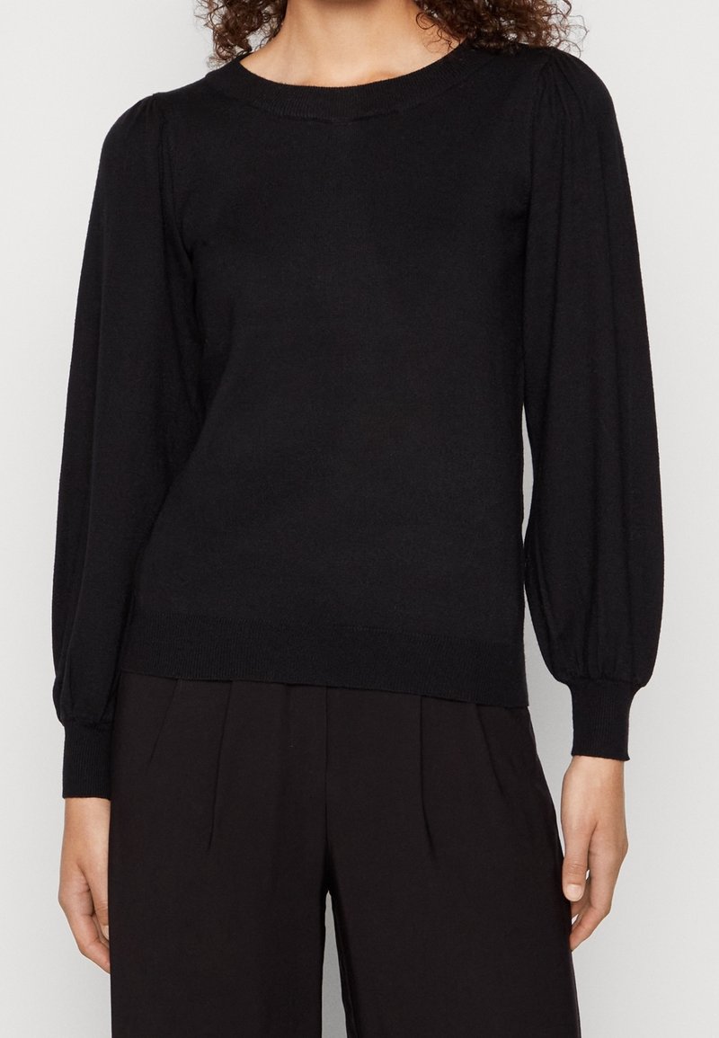 Maglione nero a maglia con maniche lunghe a sbuffo e polsini a costine. Presenta uno scollo rotondo e una silhouette aderente. Texture morbida.