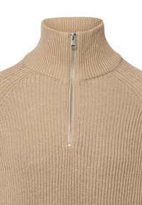 Beige geribbelde sweater met een hoge kraag en een korte zilveren rits. Beschikt over een textuur gebreid patroon en raglan mouwontwerp.