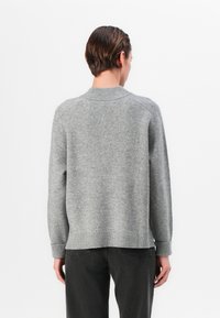 Grauer gestrickter Pullover mit einem gerippten Kragen und Saum. Verfügt über Raglanärmel und eine weiche Textur. Von hinten vor einem schlichten Hintergrund präsentiert.
