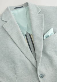 Hellgrauer strukturierten Blazer mit gemusterter hellblauer Futterung und passender Tasche, ein-Knopf-Verschluss und Reverskragen.