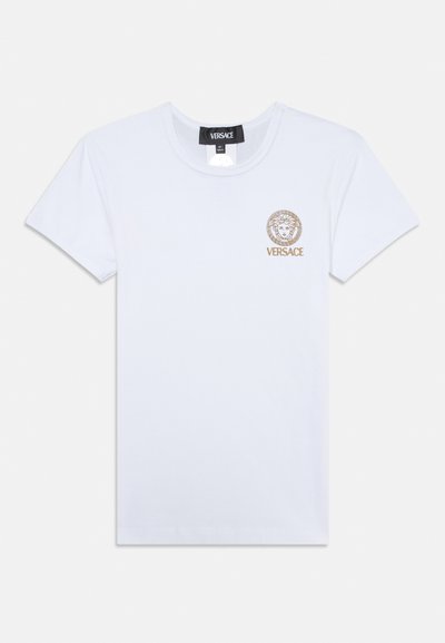 Valge puuvillane T-särk, millel on ümar kaelus, lühikesed varrukad ja vasakus rinnas kuldse trükitud Medusa logo, millel on ümmargune äär.