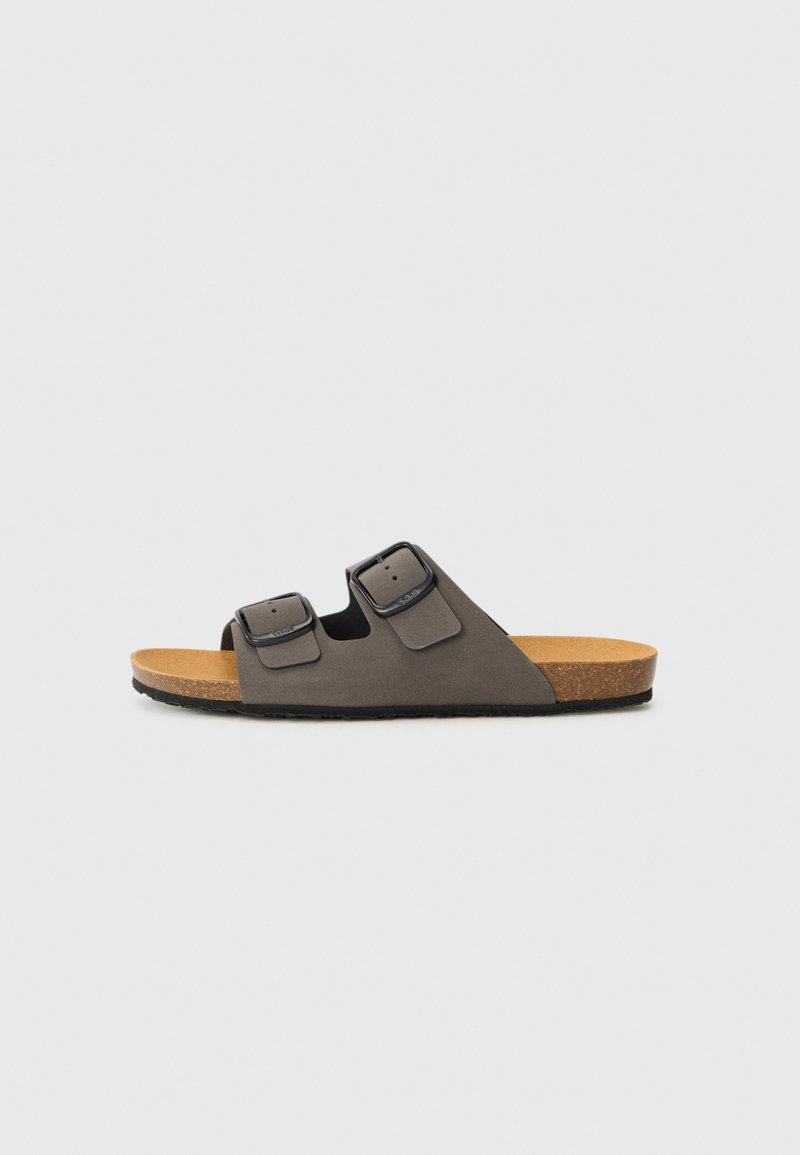 Sandales glissantes grises avec deux sangles ajustables, semelle en liège, semelle en caoutchouc et texture lisse. Design minimaliste avec quincaillerie fonctionnelle.