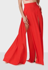 Pantalones rojos de pierna ancha con aberturas laterales y una cintura alta. Fabricados en una tela suave y fluida, presentan un diseño drapeado que permite libertad de movimiento.