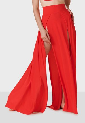 Red wide-leg pants with side slits and a high waistband. Made from a smooth, flowing fabric, they feature a draped design for ease of movement.