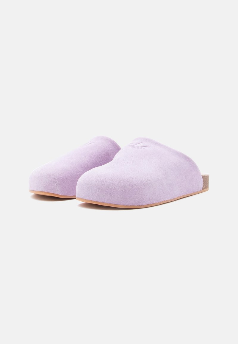 Purple suede slip-on clogs with rounded toes and a flat sole. The interior features minimal stitching and a natural wood accent at the heel.