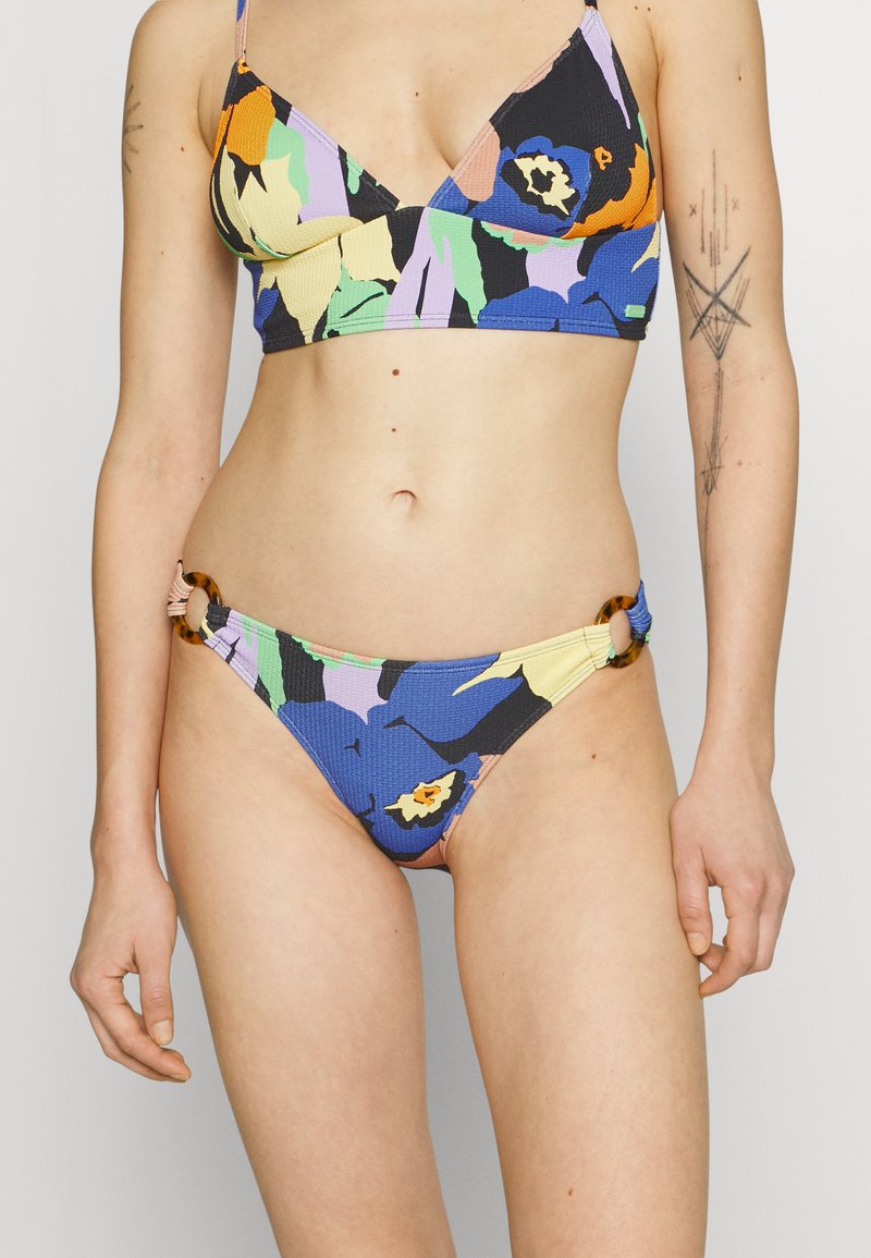 Bikini komplet v več barvah, ki vsebuje teksturirano tkanino z cvetličnimi vzorci. Zgornji del ima obliko trikotnika, spodnji del pa vključuje okrogle dodatke.