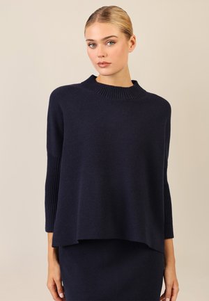 Dunkelblauer Strickpullover mit einem gerippten Kragen und Ärmeln, der eine lässige Passform und eine glatte Textur aufweist. Keine sichtbaren Muster oder Beschläge.