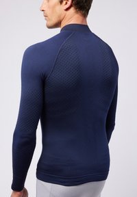 Marineblauwe sportieve longsleeve shirt met een gestructureerd patroon op de achterkant en de mouwen, met een ronde hals en een getailleerd ontwerp voor ondersteuning.
