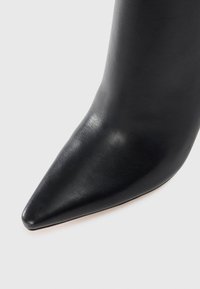 Sorte læder ankelstøvler med spids tå og glat overfladetextur, der har en glat, skinnende finish. Designet fokuserer på minimalistisk æstetik.