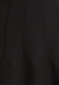 Tissu noir de robe avec un design texturé et structuré, présentant des coutures diagonales et un motif en chevron en bas. Texture douce et lisse.