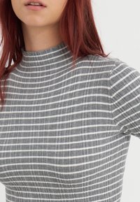Szary i biały pasiasty sweter w prążki z golfem, o dopasowanym kroju, z wysokim kołnierzem i krótkim rękawem.