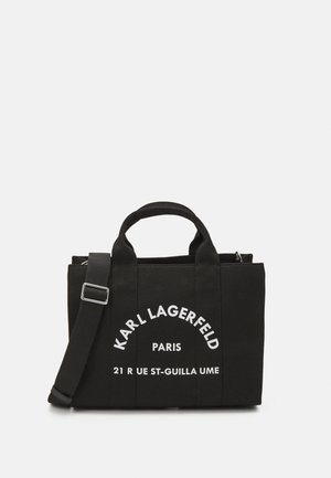 Czarna torba na ramię z płótna z dwoma uchwytami i odpinanym paskiem na ramię. Ozdobiona białym nadrukiem: "KARL LAGERFELD PARIS 21 RUE ST-GUILLAUME."