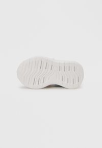 Biela podrážka tenisky s textúrovaným vzorom obsahujúcim drážky a výrezy pre lepšiu priľnavosť, navrhnutá pre ľahkosť, pohodlie a flexibilitu.