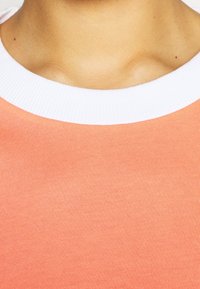 Short-sleeved shirt with a ribbed white collar, in a light coral color, featuring a smooth texture and a fitted design.