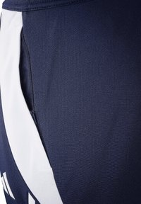 Marineblauwe sportbroek met een wit zijpaneel en een ritszak, gemaakt van een gladde, gestructureerde stof met een ademend ontwerp.