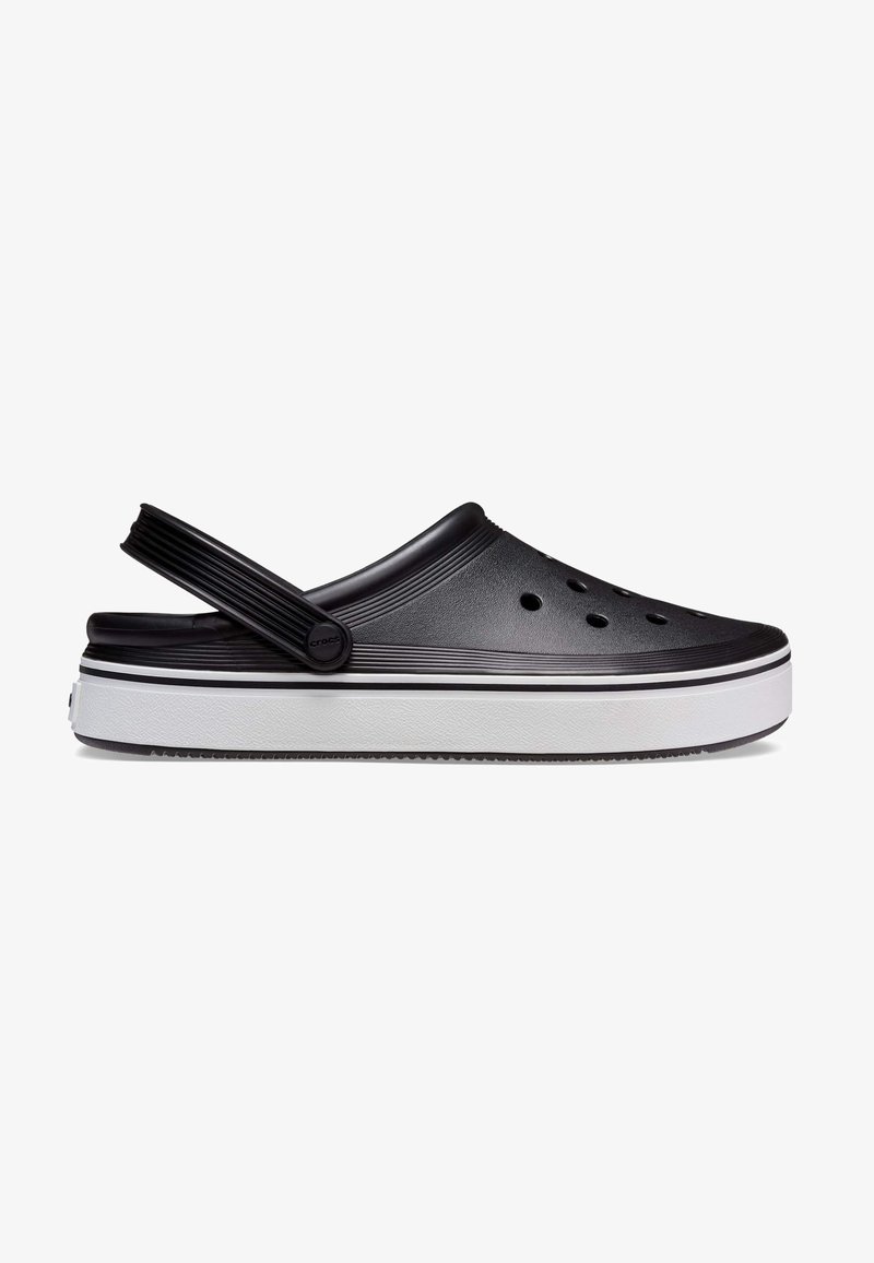 Sabot noir à enfiler avec des trous d'aération, une semelle blanche épaisse avec des rayures noires et une bride mobile au talon.