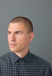 Camicia a quadri nera e grigia con colletto appuntito, caratterizzata da due bottoni frontali e una texture di tessuto liscia.