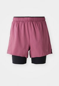 Pink athletic shorts over black stretching shorts, featuring an elastic waistband, side slits, and a small logo on the lower hem.