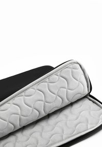 Schwarze Reißverschlusstasche mit einem grauen quilted Innenraum, der ein wellenförmiges Muster auf weichem Stoff aufweist, entworfen für Schutz und Aufbewahrung.
