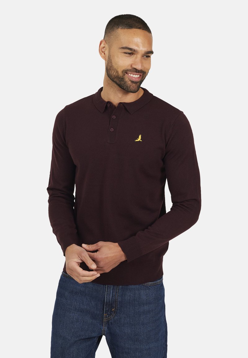 Polo a maniche lunghe bordeaux con colletto, tre bottoni e un piccolo logo di uccellino giallo sul lato sinistro del petto. Tessuto misto cotone, polsini a costine.