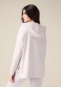 Felpa con cappuccio grigio chiaro, dal taglio morbido, con spacchi laterali e polsi a costine. Tessuto dallasuperficie liscia, design minimalista.