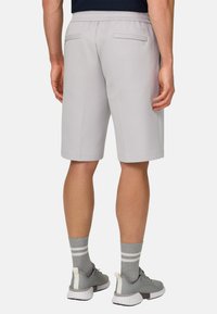 Hellgraue Sportshorts mit elastischem Bund und zwei Gesäßtaschen. Kombiniert mit grauen Schuhen und gestreiften Socken.