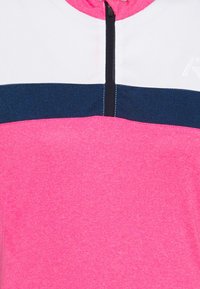 Krátký svetr na zip s krémově růžovým materiálem, bílou horní částí a tmavě modrým vodorovným proužkem. Hladká textura s kontrastním šitím.