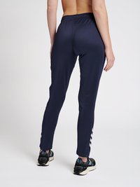 Navy sportbroeken hebben een fitted ontwerp, een elastische tailleband en contrasterende witte strepen langs de onderzijden.