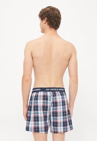 Rutete boksershorts med en marineblå midje med "JACK & JONES" i hvitt. Laget av lett stoff med et rutete mønster.