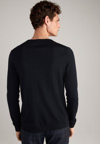 Marineblauer, langärmeliger Pullover mit Rundhalsausschnitt und geripptem Saum. Weiche Textur mit figurbetonter Form, von der Seite und von hinten gezeigt.