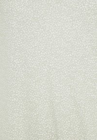 Světle zelená tkanina s jemným bílým abstraktním skvrnitým vzorem, který vytváří měkký texturovaný vzhled.