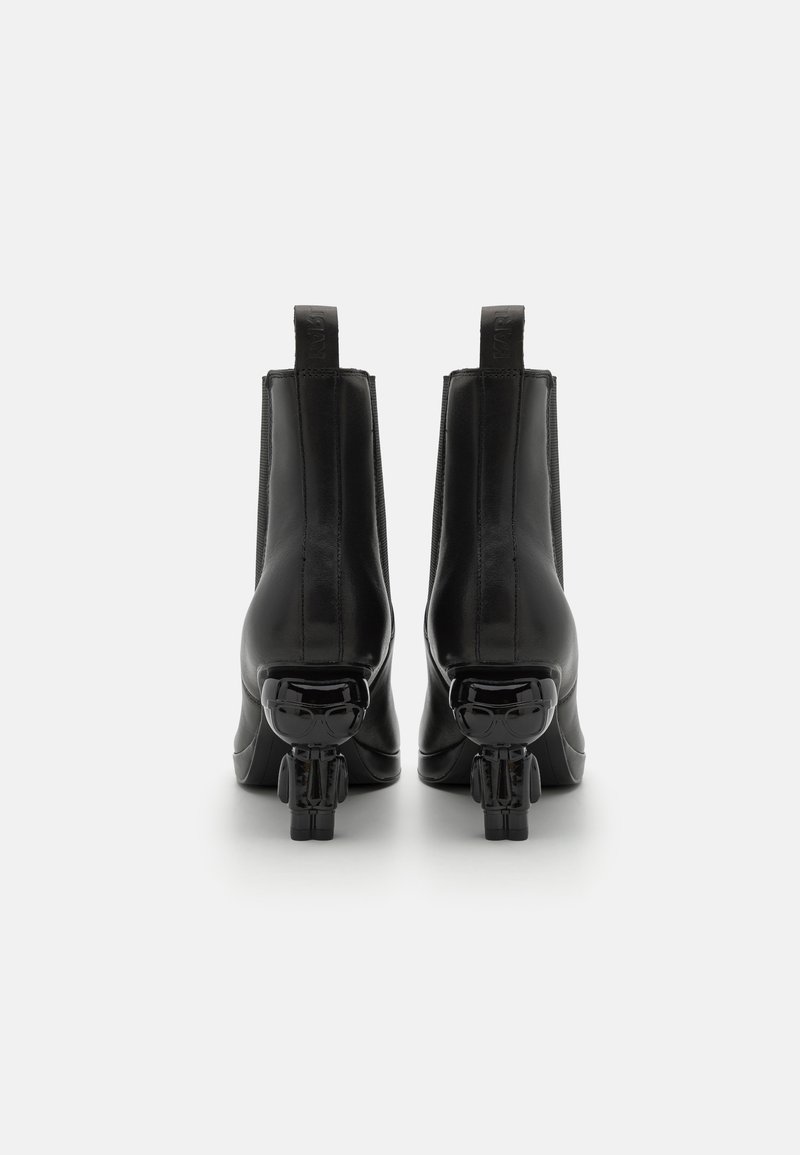 Bottines en cuir noir avec une finition lisse, dotées d'un talon en forme de skull unique. Comprend des panneaux élastiques sur les côtés et des tirettes au talon.