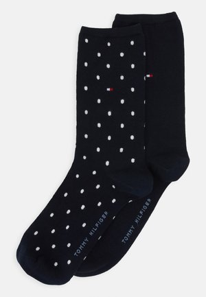 Calcetines azules marinos con lunares blancos; confeccionados con tejido suave. Cuentan con el logo de la marca en rojo, blanco y azul; textura lisa, longitud media hasta la pantorrilla.