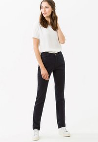 Donkerblauwe katoenen broek met een recht model, voorzakken en een knoopsluiting. Gecombineerd met een witte top met korte mouwen en sneakers.