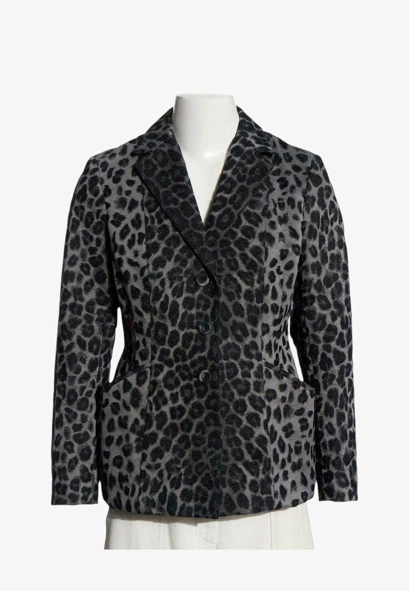 Veste imprimée léopard noire et grise avec revers crantés, trois boutons devant et deux poches latérales sur un buste de mannequin blanc.