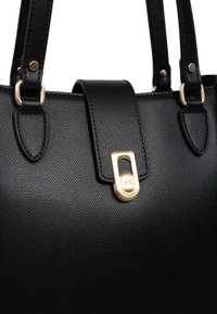 Borsa a mano in pelle nera con superficie testurizzata, dotata di hardware dorato, doppi manici e chiusura magnetica.