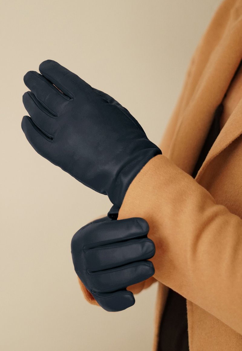 Guanti blu navy realizzati in un materiale morbido, con un design aderente a cinque dita e dettagli di cucitura sottili.