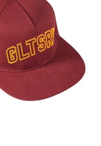 Weinrote Kappe mit flachem Schild, auf der Vorderseite mit gelbem gesticktem Text "GLTSRY". Hergestellt aus strukturiertem Stoff.
