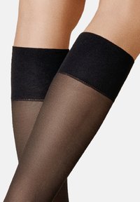 Schwarze, oberschenkellange Strümpfe mit matter Oberfläche. Das obere Band ist fest und opak, während der untere Teil transparent und glatt ist.