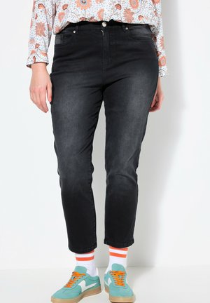Černé džíny z denimu s úzkým střihem, které mají pět kapes, zapínání na knoflík a zip a vybledlou texturu, spárované s barevnými teniskami.