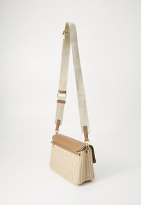 Crossbody bag featuring a tan faux leather top, woven beige body with grid pattern, adjustable beige fabric strap, and gold hardware accents.