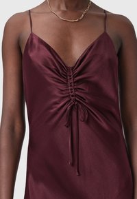 Burgundy satin klänning med V-ringning och rynkning i mitten, med tunna band och en knytning i botten. Slät textur.