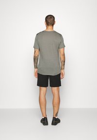 Grå kortärmad t-shirt med klassisk rund halsringning, i kombination med svarta shorts. Tyget verkar mjukt med en avslappnad passform.