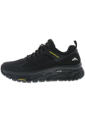 Schwarzer wasserabweisender Sportschuh mit strukturiertem Obermaterial, Schnürsystem, gepolsterter Sohle und auffälligen "ArchFit"- und "Goodyear"-Markierungen.
