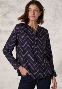 Maglietta nera a maniche lunghe con un motivo a zigzag viola, dotata di colletto a intaglio e dettagli con bottoni lungo la patta anteriore.
