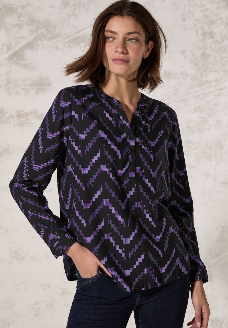 Maglietta nera a maniche lunghe con un motivo a zigzag viola, dotata di colletto a intaglio e dettagli con bottoni lungo la patta anteriore.